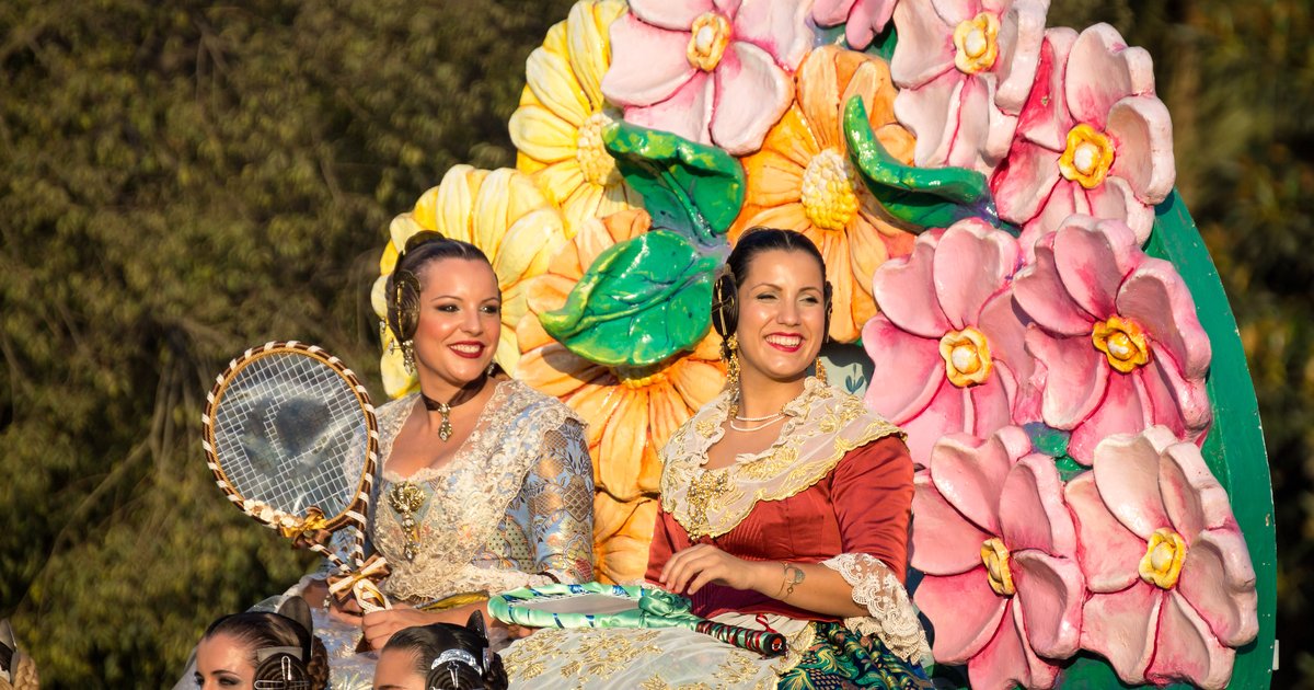 Falleras in traditional dress on a flower-covered float at the Batalla de Flores during the Gran Fira de Valencia